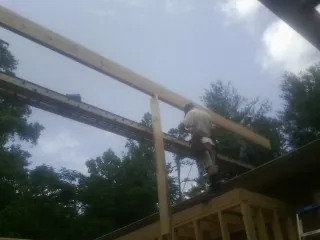 Carpenter setting a ridge beam over a new addition frame — Ice Dam Removal by Roofing Brothers in Devens