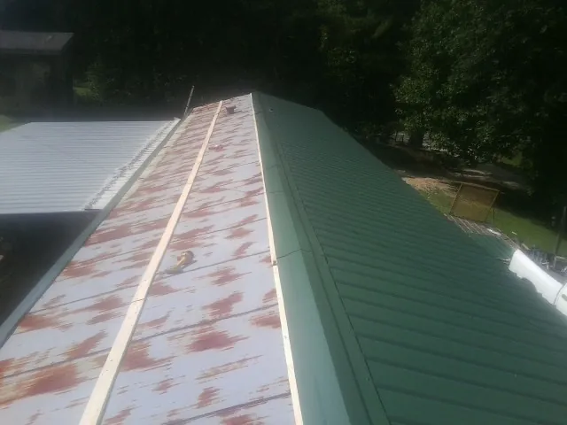 Old rusted panels beside newly installed green metal roofing — Wind Damage Roof Repair by Roofing Brothers in Devens