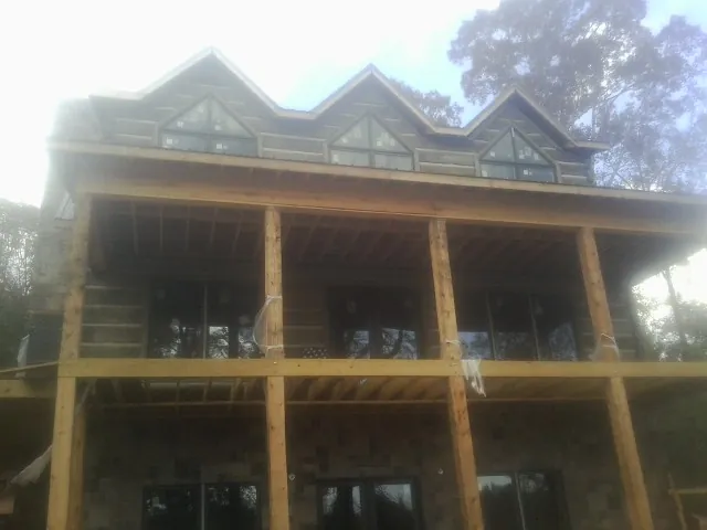 Dormers and porch framing on a large log home under construction — Roof Coating work by our crew in Devens