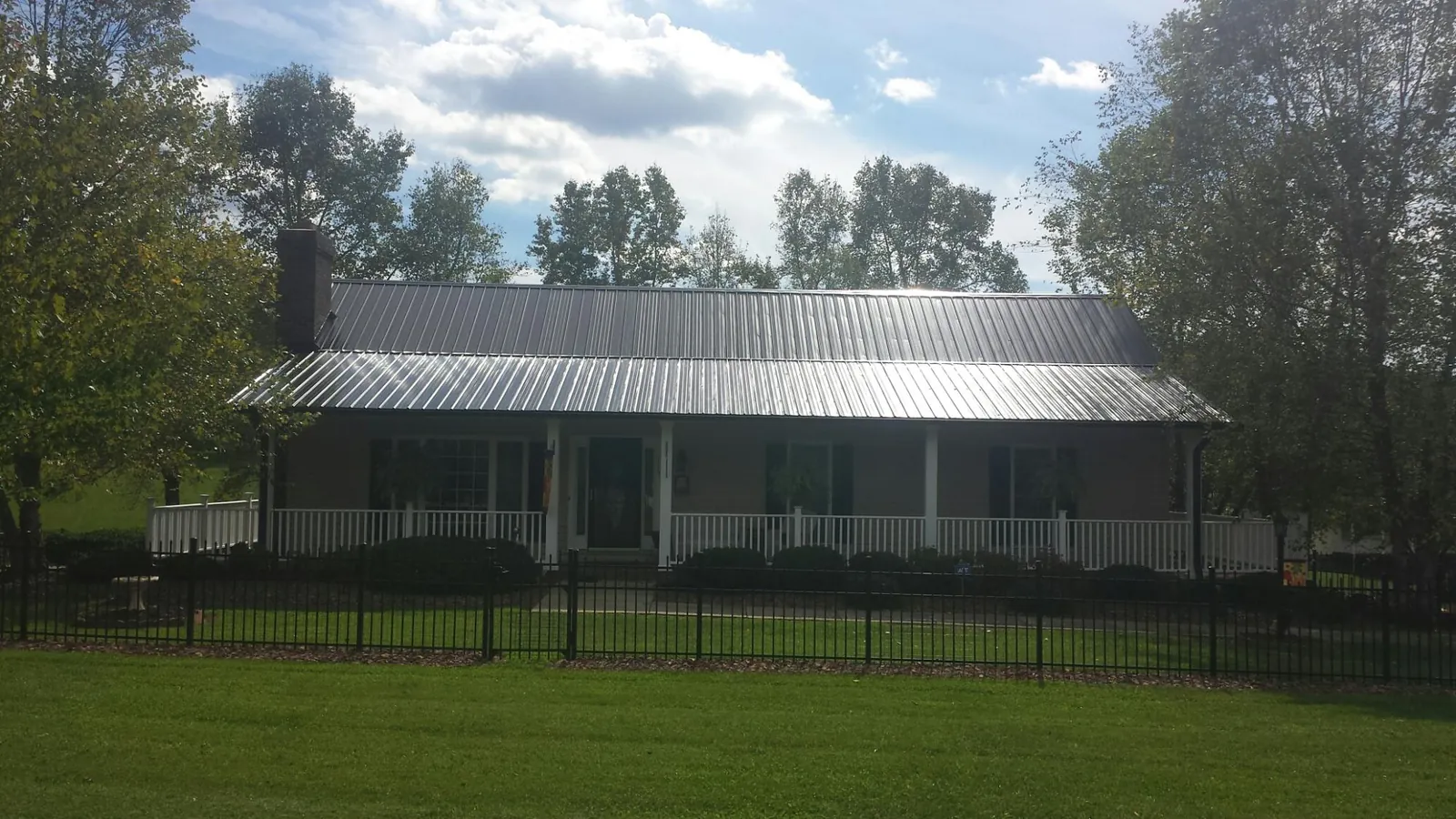 Gray metal roof on a brick ranch with a full width front porch — Gutter Guard Installation work by our crew in Devens