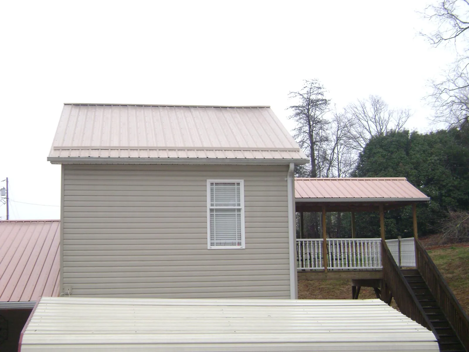 Tan metal roofs on a two story addition and attached porch in Devens